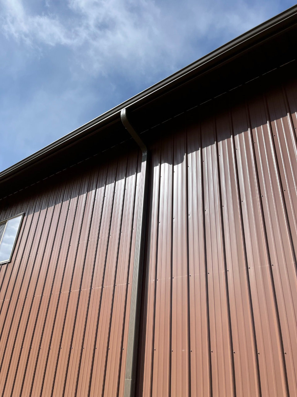 Brown metal building with seamless gutter and downspout